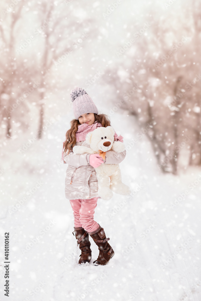 Little girl with a teddy bear stands on the street under the flying snow. winter day Little girl with a teddy bear stands on the street under the flying snow. winter day