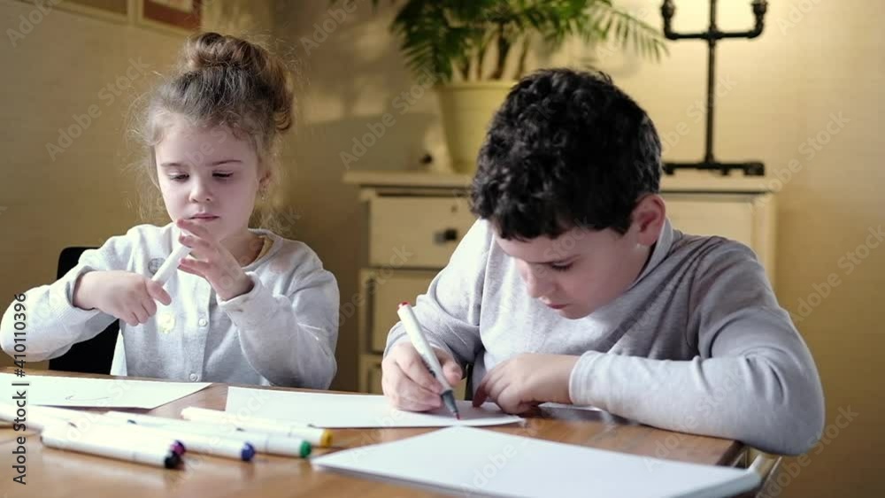 Children draw pictures with colored pencil on paper in bright living room. concept of preschool child development. Teaching children to draw school and home. development of imagination and creativity Children draw pictures with colored pencil on paper in bright living room. concept of preschool child development. Teaching children to draw school and home. development of imagination and creativity
