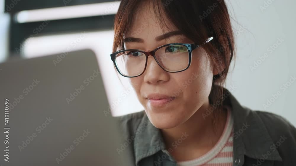 A positive asian woman is working with a laptop in the office A positive asian woman is working with a laptop in the office