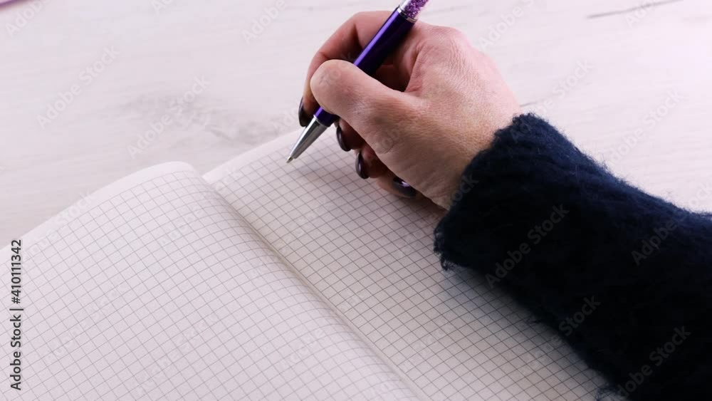 A woman opens the notbook and prepares to write notes in it. 