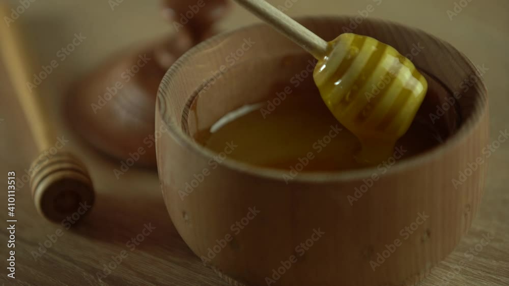 Thick honey dripping from the spoon, close up. Honey flowing honey from a spoon