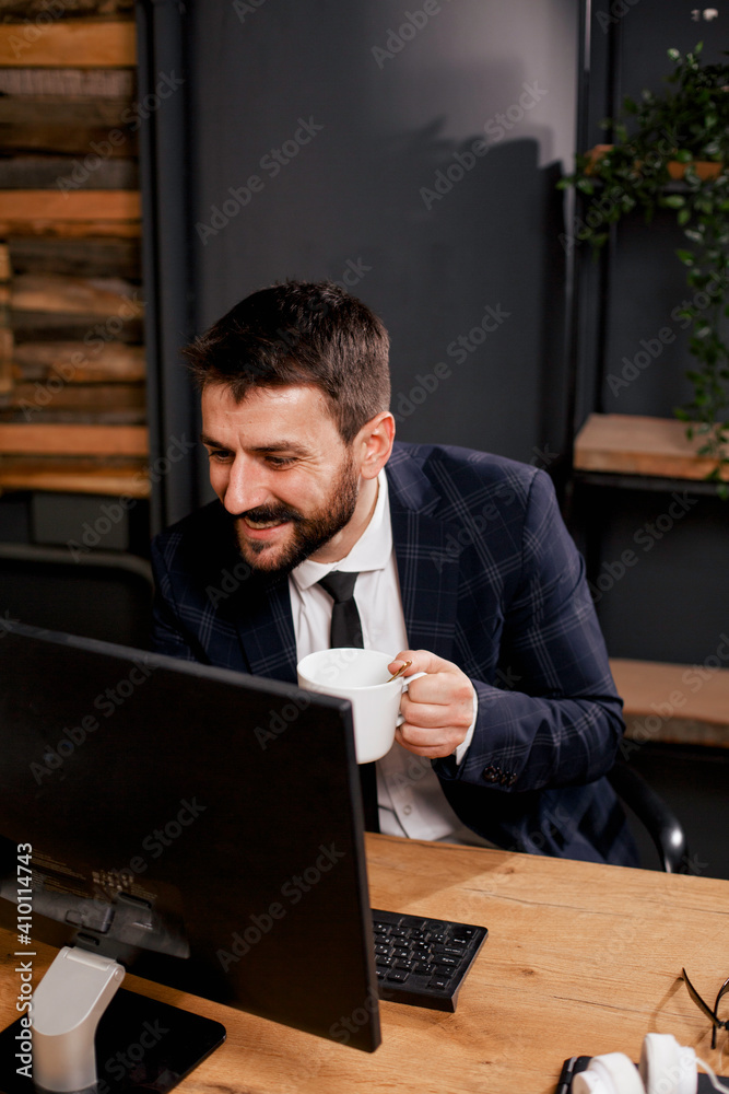 Young businessman using computer in his office. Handsome man on coffee break. Young businessman using computer in his office. Handsome man on coffee break.