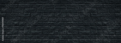 Wide old black shabby brick wall texture. Cracked masonry panorama. Dark rough brickwork grunge background