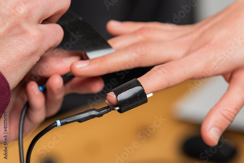 close-up, a man puts on a woman's hand polygraph sensors, a truth detector, to pass a polygraph. Selective focus