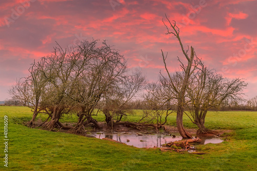 A fiery sunset above a dew pond in winter near Lubenham, UK photo