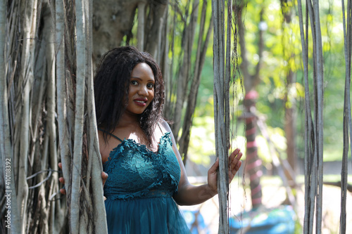 Cheerful young woman standing by tree in the jungle.