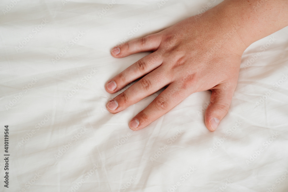 man's hand on a white bed sheet. skin care products. cosmetics, cream and medicines for itching, allergies. man's hand on a white bed sheet. skin care products. cosmetics, cream and medicines for itching, allergies.