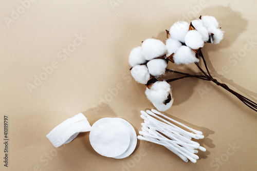 fluffy cotton flower cotton pads and cotton swabs on beige background with copy space. hygienic disposable product