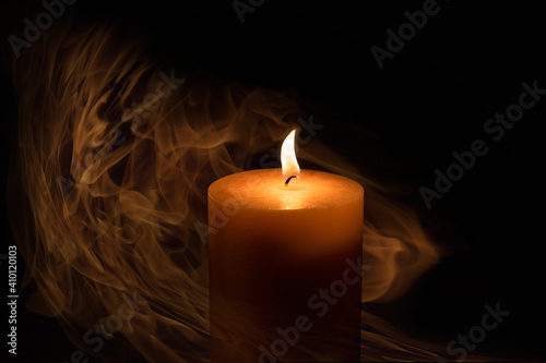 Candle flame close-up on a dark background. The candle burns in the dark, it is enveloped in smoke