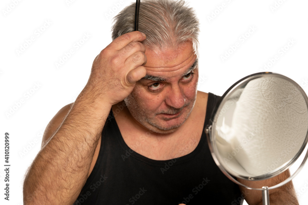 middle aged man combing his short gray hair middle aged man combing his short gray hair