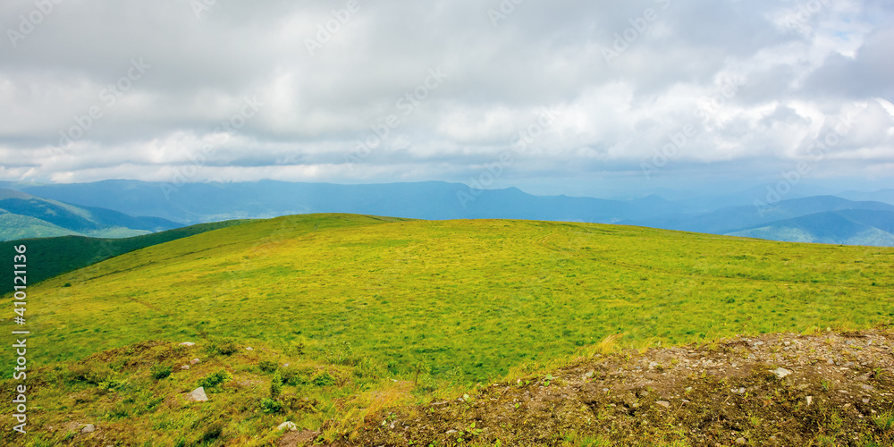 mountain landscape in summer on a cloudy day. grass covered hillside meadow. carpathian watershed ridge in the distance mountain landscape in summer on a cloudy day. grass covered hillside meadow. carpathian watershed ridge in the distance