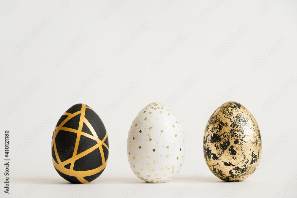 Three Easter golden decorated eggs isolated on white background. Minimal easter concept. Happy Easter card with copy space for text. Top view, flatlay. Three Easter golden decorated eggs isolated on white background. Minimal easter concept. Happy Easter card with copy space for text. Top view, flatlay.