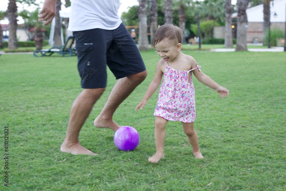 A little girl plays in the summer with her dad in a ball in the meadow. Retro processing with added noise. A little girl plays in the summer with her dad in a ball in the meadow. Retro processing with added noise.
