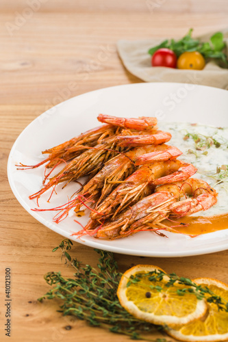 King shrimp in cream sauce in a plate on a light wooden background.