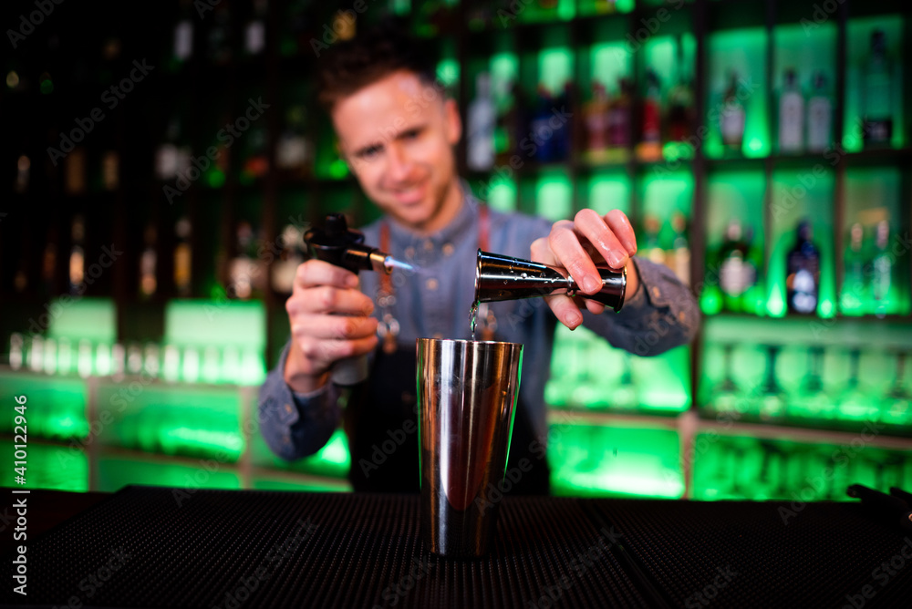 Young guy working as a bartender preparing cocktails in a pub