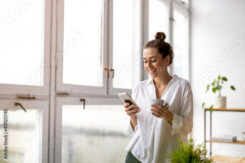 Creative business woman using smartphone in loft office
