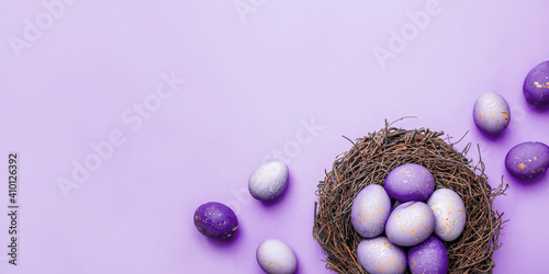 Photography Easter eggs in nest on purple background. Flat lay, top view.