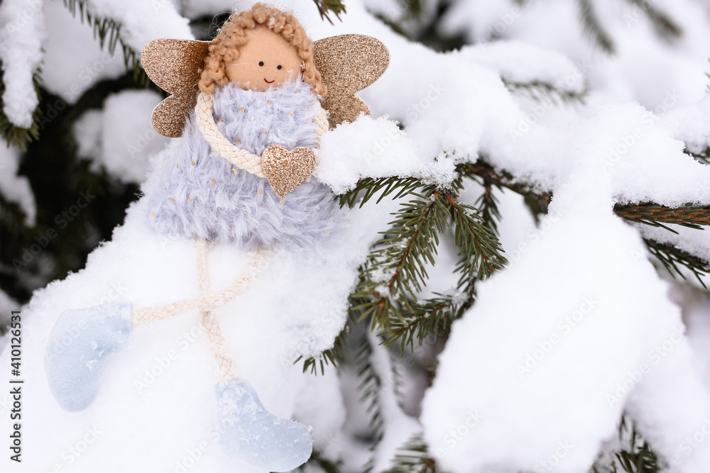 A soft textile doll with golden heart in hands sitting on the snow. Valentine’s Day, love, Merry Christmas, New Year concept.