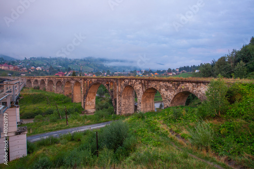 Arched old brick railway bridge in the picturesque mountains among the forest of meadows tourist trail Carpathians