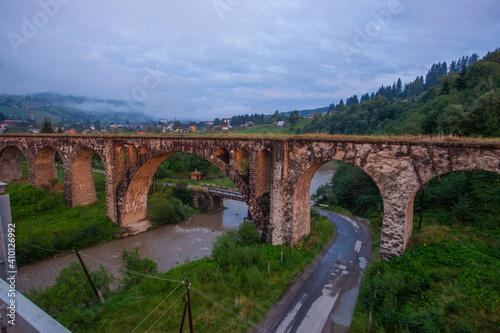 Arched old brick railway bridge in the picturesque mountains among the forest of meadows tourist trail Carpathians