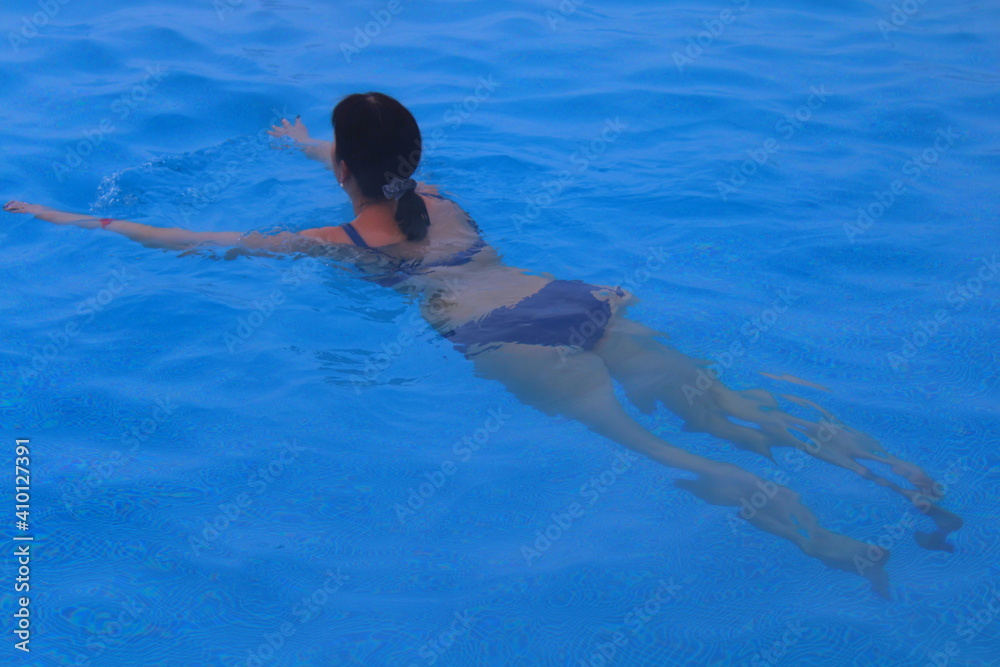 a girl in a swimsuit swims in the pool