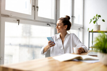 Creative business woman using smartphone in loft office
