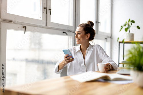 Creative business woman using smartphone in loft office
 photo