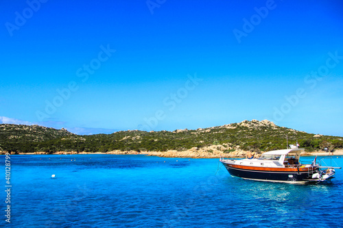 photo of a boat anchored in the mediterranean sea near a beach 