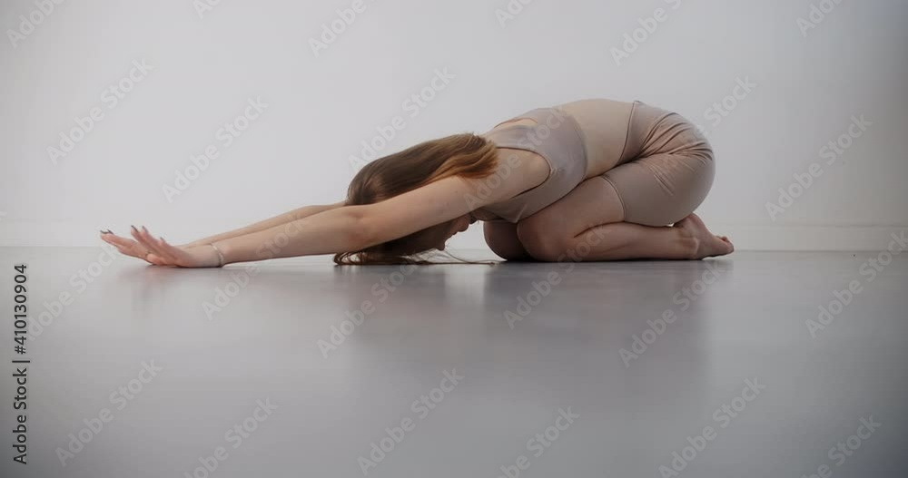 Yoga instructor does exercises on the floor in slow motion, young woman in beige costume does pilates and stretching exercises on the white background, 4k 120p Prores HQ Yoga instructor does exercises on the floor in slow motion, young woman in beige costume does pilates and stretching exercises on the white background, 4k 120p Prores HQ