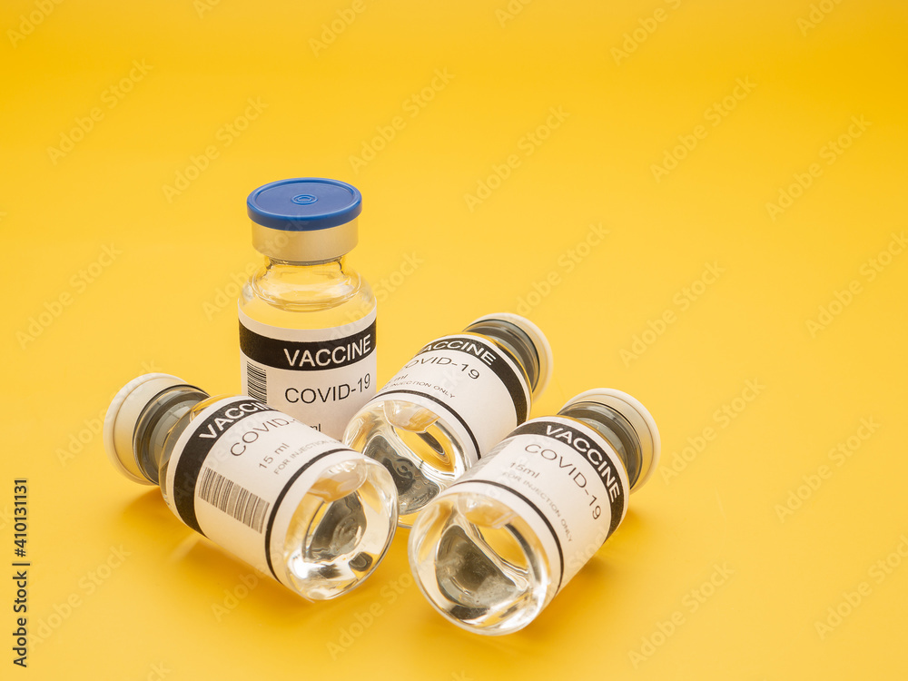 Top view of the covid-19 vaccine in glass bottles for prevention, immunization, and treatment from coronavirus infection on yellow background. Space for text. Concept of medical and vaccine Top view of the covid-19 vaccine in glass bottles for prevention, immunization, and treatment from coronavirus infection on yellow background. Space for text. Concept of medical and vaccine