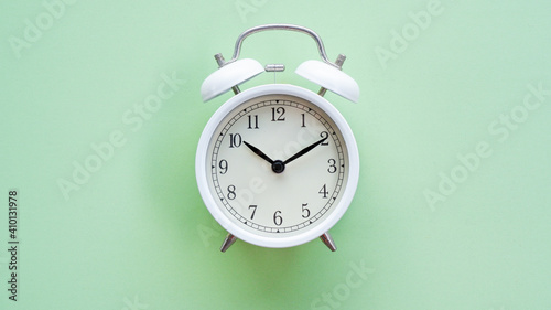 Vintage white alarm clock watch over soft pastel green color background