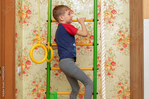 A small child goes in for sports on the wall bars.