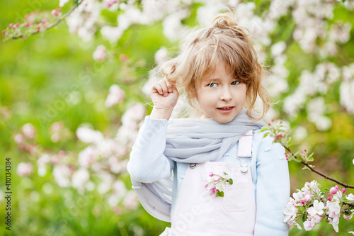Beautiful preteen girl with long blond hair enjoy spring apple blooming. Little preschool girl in garden tree flowers. Springtime. Copy space