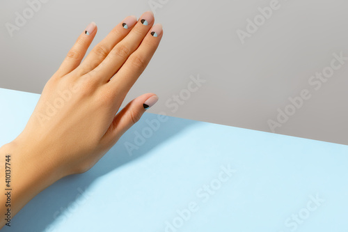 Beautiful groomed womans hand with nude and blue matte nail design