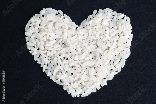 Diet food concept. Love for rice. Heart shaped uncooked rice isolated on black background, closeup, top view. Can be used as a symbol of Thai, Japanese, Pan-Asian, Vietnamese cuisine