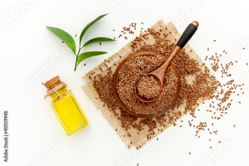 Flax seeds in a spoon and bowl with a bottle of flaxseed oil