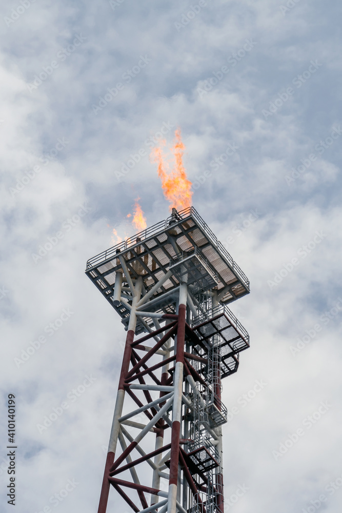 Obraz premium Flare torch on a tower burning excess gas from an oil production platorm at offshore oil field