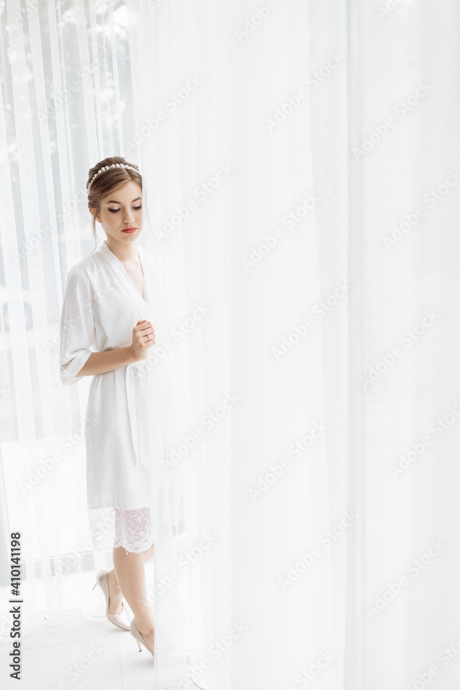 beautiful bride with a white robe is going at home. fees of the bride. wedding day of the newlyweds. a hoop on the bride's head. decoration on the girl's head. wedding bouquet of flowers. beautiful bride with a white robe is going at home. fees of the bride. wedding day of the newlyweds. a hoop on the bride's head. decoration on the girl's head. wedding bouquet of flowers.