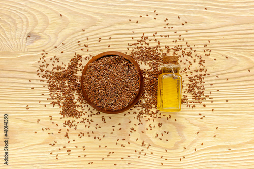 Flax seeds in a spoon and bowl with a bottle of flaxseed oil
