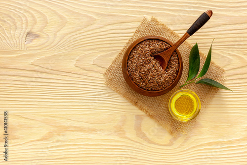 Flax seeds in a spoon and bowl with a bottle of flaxseed oil