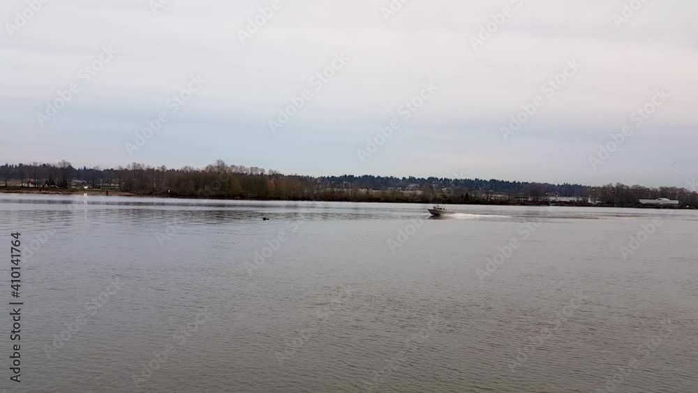 Low angle shot of suspension bridge while small speeding boat cruising by the river and cars and trucks crossing the bridge Low angle shot of suspension bridge while small speeding boat cruising by the river and cars and trucks crossing the bridge