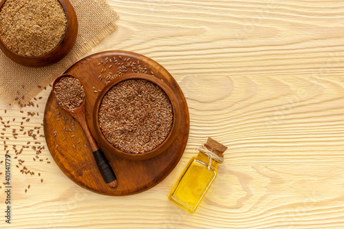 Flaxseeds in a spoon and bowl with a bottle of flaxseed oil and flaxseed flour