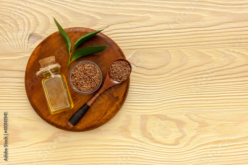 Flax seeds in a spoon and bowl with a bottle of flaxseed oil