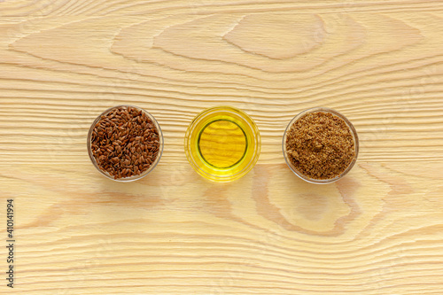 Flaxseeds in a spoon and bowl with a bottle of flaxseed oil and flaxseed flour