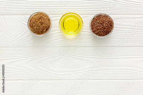 Flaxseeds in a spoon and bowl with a bottle of flaxseed oil and flaxseed flour