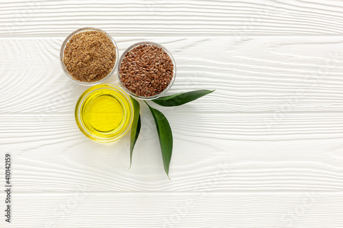 Flaxseeds in a spoon and bowl with a bottle of flaxseed oil and flaxseed flour