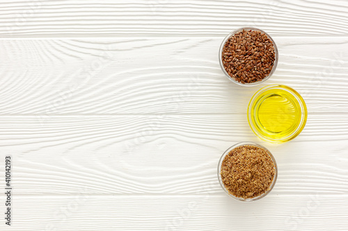 Flaxseeds in a spoon and bowl with a bottle of flaxseed oil and flaxseed flour