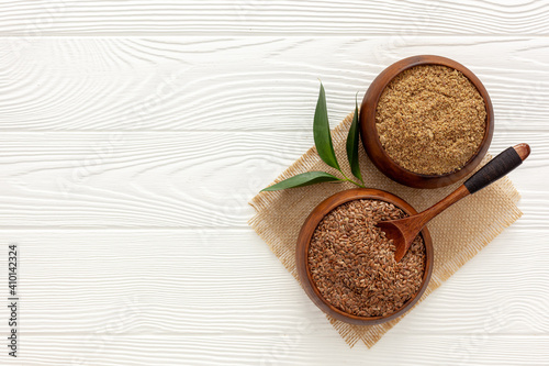 Flaxseeds in a spoon and bowl with a bottle of flaxseed oil and flaxseed flour