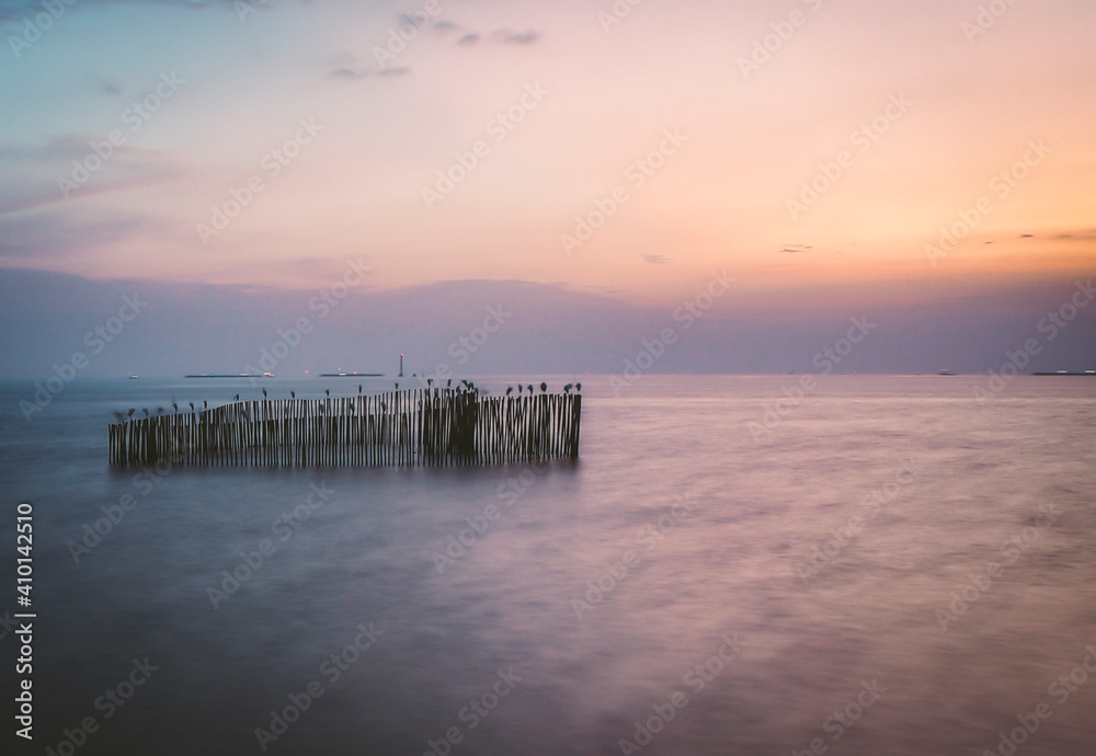 long exposure wooden pole in sea at dusk. Pastel blue and pink sky in Bangpu Thailand