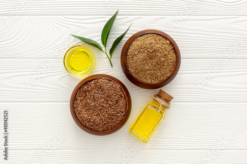 Flaxseeds in a spoon and bowl with a bottle of flaxseed oil and flaxseed flour